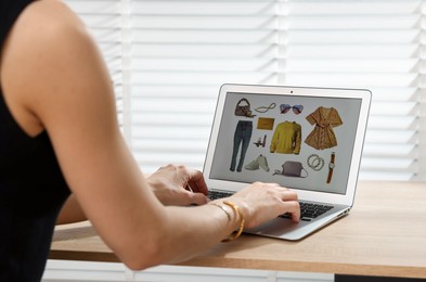 Photo of Professional stylist making collage with outfit on laptop at desk indoors, closeup