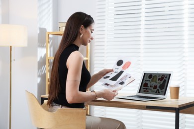 Photo of Professional stylist making collage with outfit on laptop at desk indoors