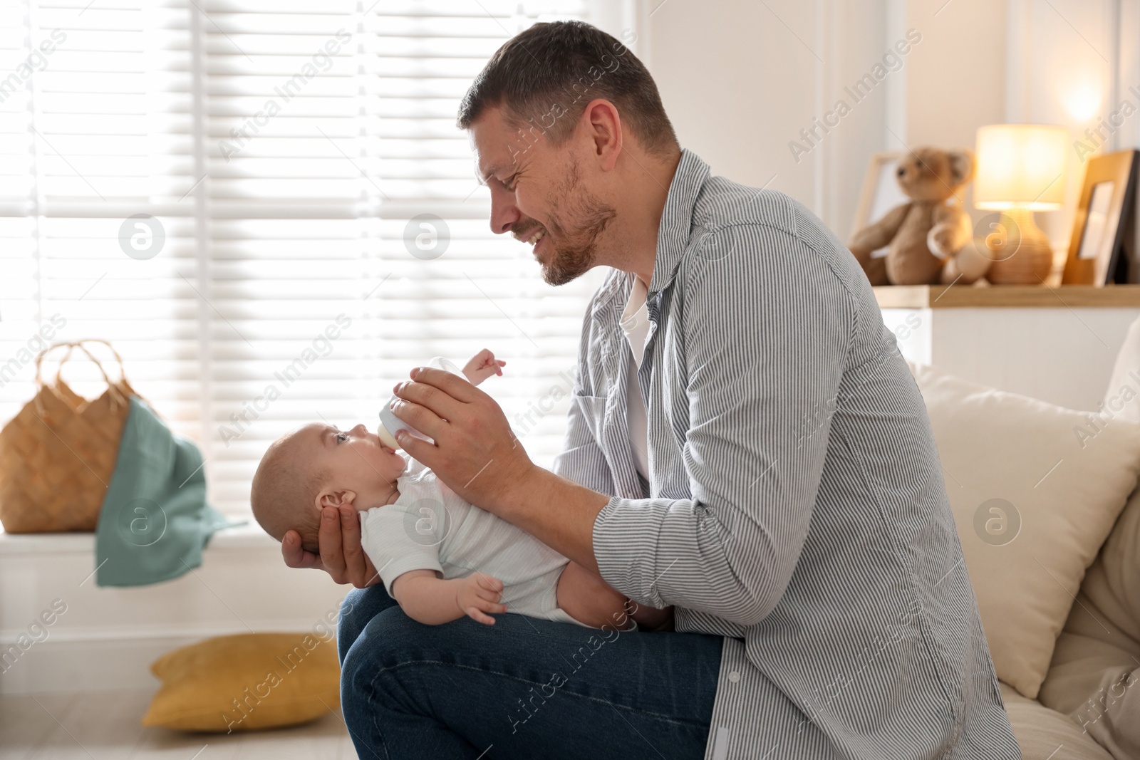 Father feeding his little baby with bottle on sofa at home Photo of Father feeding his little baby with bottle on sofa at home