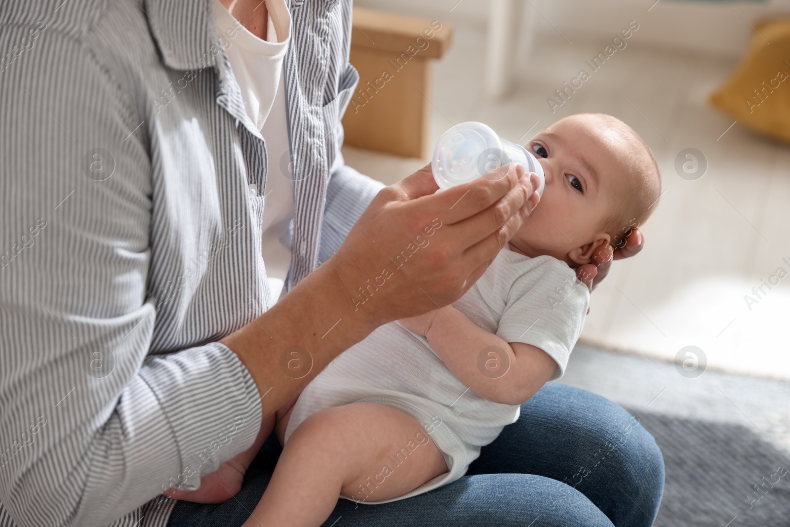Father feeding his little baby with bottle on sofa at home, closeup Photo of Father feeding his little baby with bottle on sofa at home, closeup