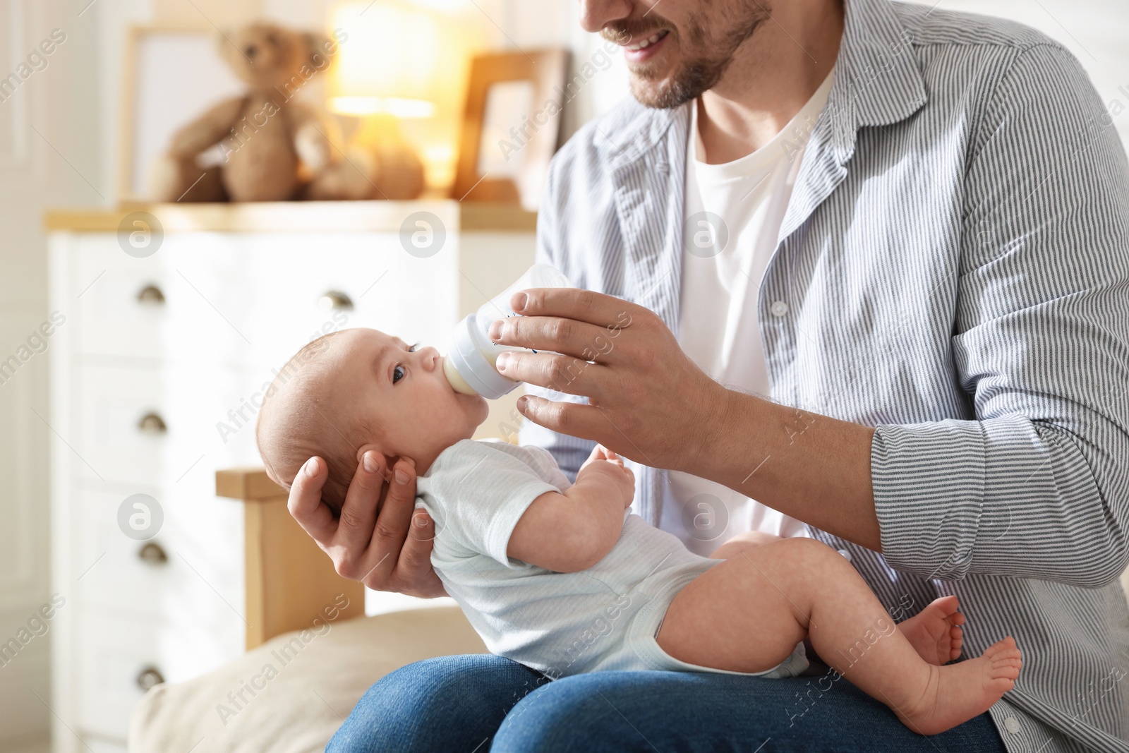 Father feeding his little baby with bottle on sofa at home, closeup Photo of Father feeding his little baby with bottle on sofa at home, closeup