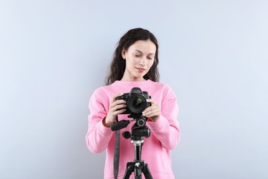 Photo of Woman with professional video camera on light grey background