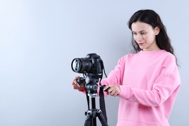 Photo of Woman with professional video camera on light grey background, space for text
