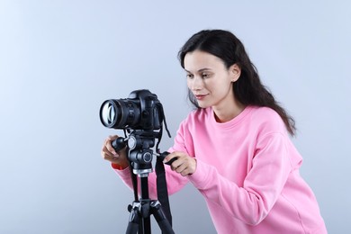 Photo of Woman with professional video camera on light grey background