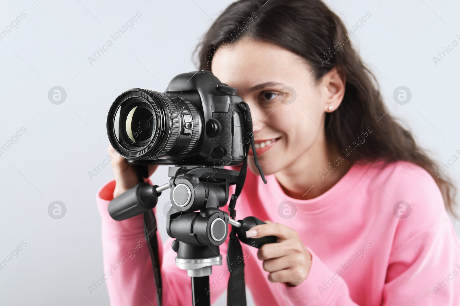 Woman with professional video camera on light grey background Photo of Woman with professional video camera on light grey background