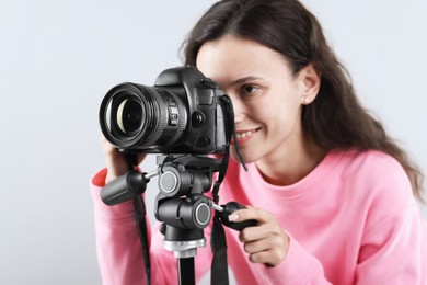 Photo of Woman with professional video camera on light grey background