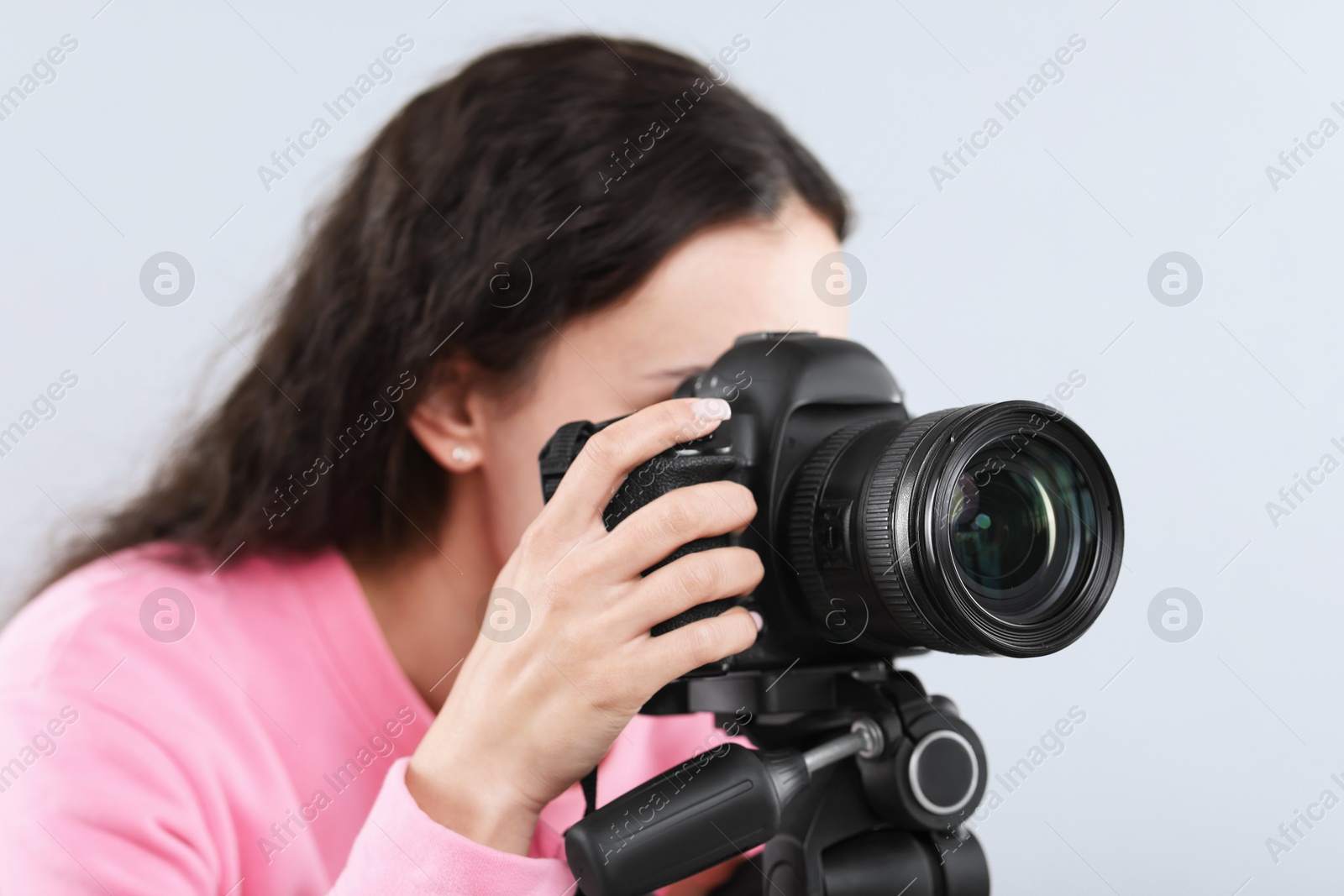 Woman with professional video camera on light grey background Photo of Woman with professional video camera on light grey background