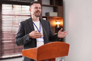 Photo of Man giving public speech with microphone at lectern indoors