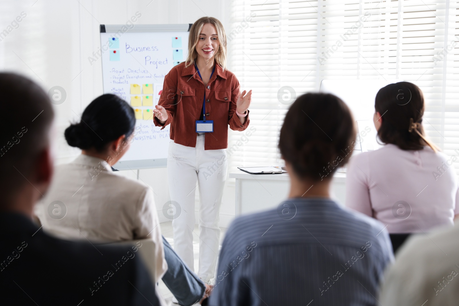 Woman giving public speech in front of audience indoors Photo of Woman giving public speech in front of audience indoors