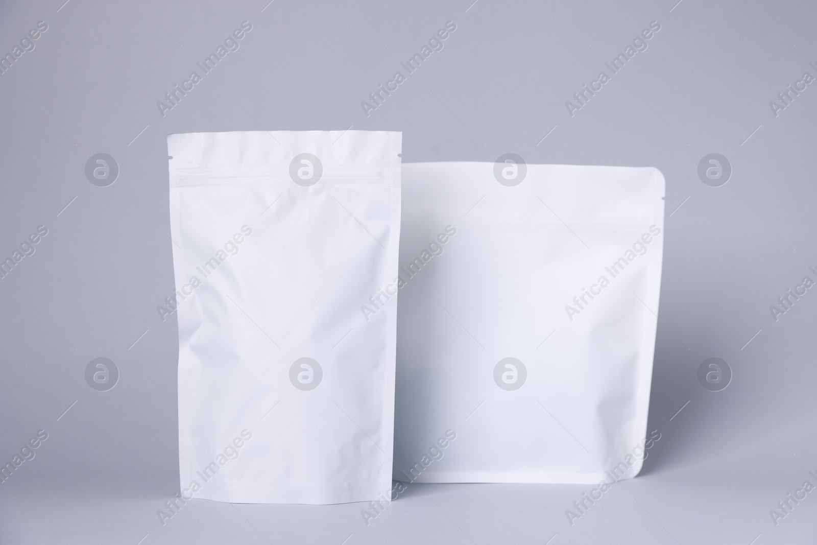Zipper stand-up pouches on light grey background. Mockup for design Photo of Zipper stand-up pouches on light grey background. Mockup for design