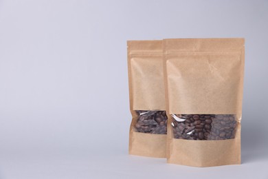 Photo of Zipper stand-up pouches with coffee beans on light grey background. Mockup for design