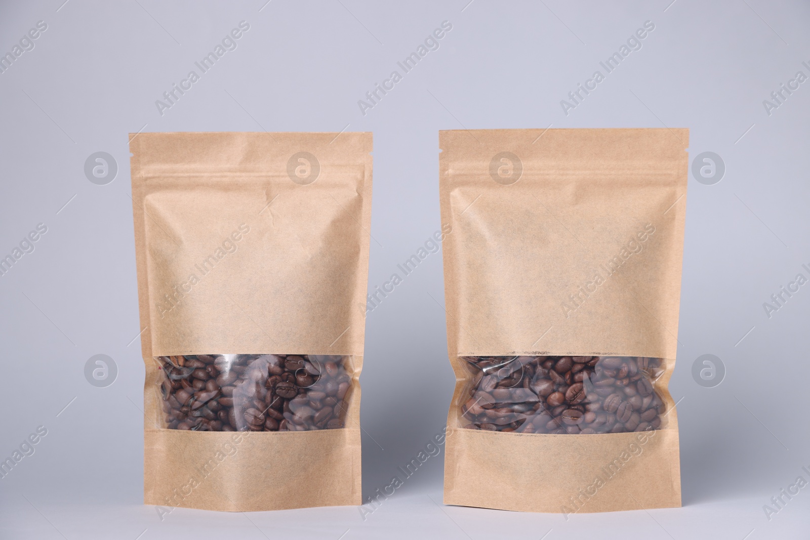 Zipper stand-up pouches with coffee beans on light grey background. Mockup for design Photo of Zipper stand-up pouches with coffee beans on light grey background. Mockup for design