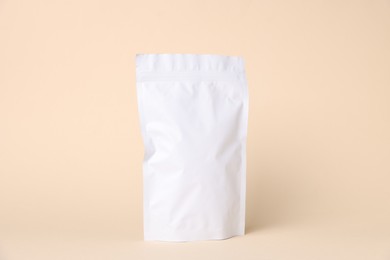 Photo of One zipper stand-up pouch on beige background. Mockup for design