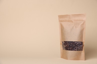 Photo of One zipper stand-up pouch with coffee beans on beige background. Mockup for design