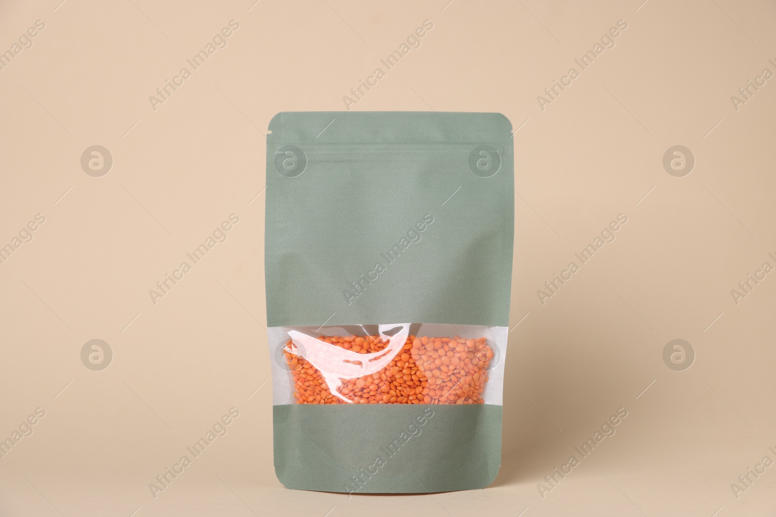 Photo of One zipper stand-up pouch with lentils on beige background. Mockup for design
