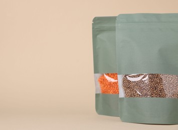 Photo of Zipper stand-up pouches with lentils and seeds on beige background, closeup. Mockup for design