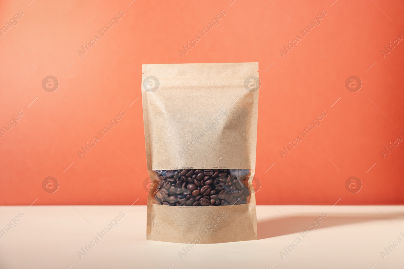 One zipper stand-up pouch with coffee beans on white table against red background. Mockup for design Photo of One zipper stand-up pouch with coffee beans on white table against red background. Mockup for design