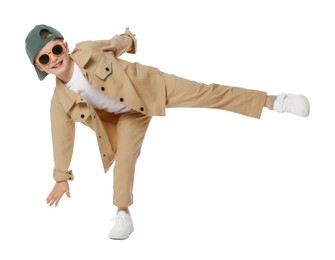 Photo of Happy little boy in sunglasses and baseball hat dancing on white background