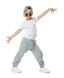 Photo of Cute little boy in sunglasses and baseball hat dancing on white background