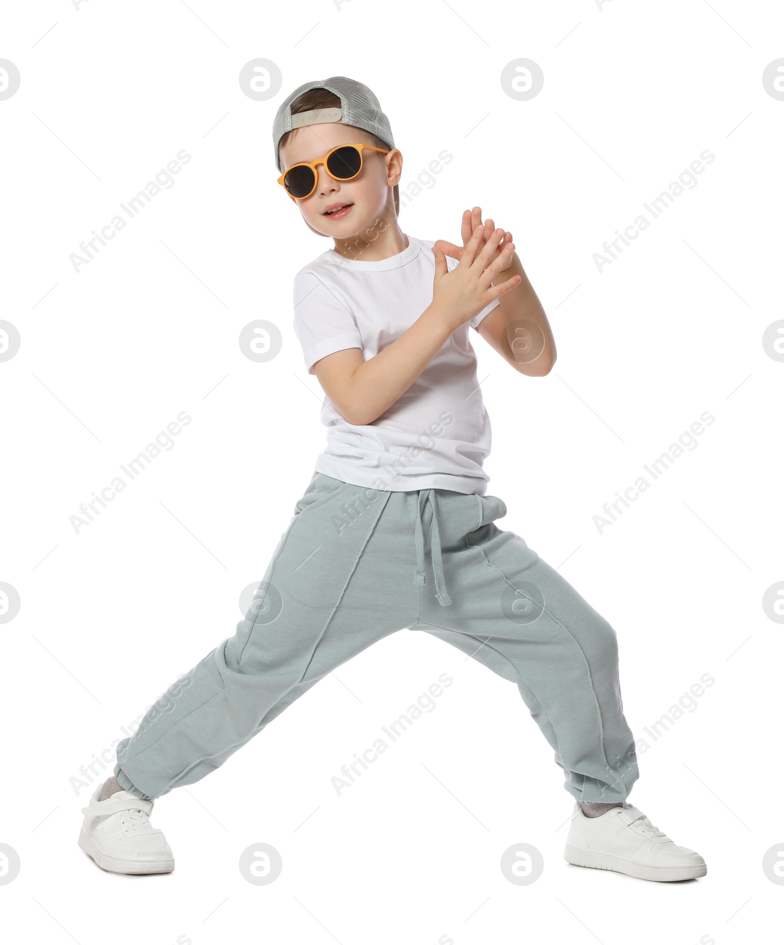 Happy little boy in sunglasses and baseball hat dancing on white background Photo of Happy little boy in sunglasses and baseball hat dancing on white background