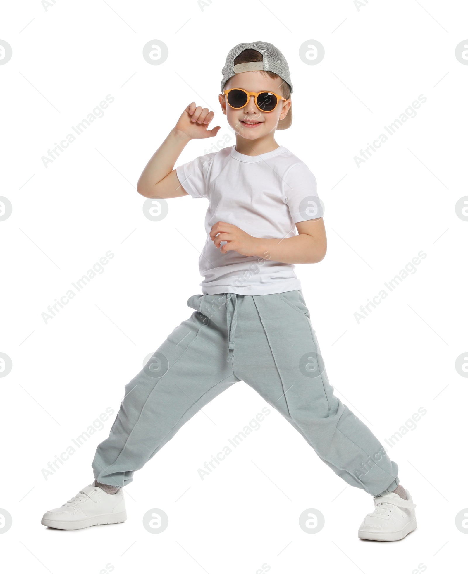 Happy little boy in sunglasses and baseball hat dancing on white background Photo of Happy little boy in sunglasses and baseball hat dancing on white background