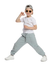 Photo of Happy little boy in sunglasses and baseball hat dancing on white background