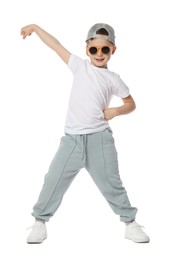 Photo of Happy little boy in sunglasses and baseball hat dancing on white background