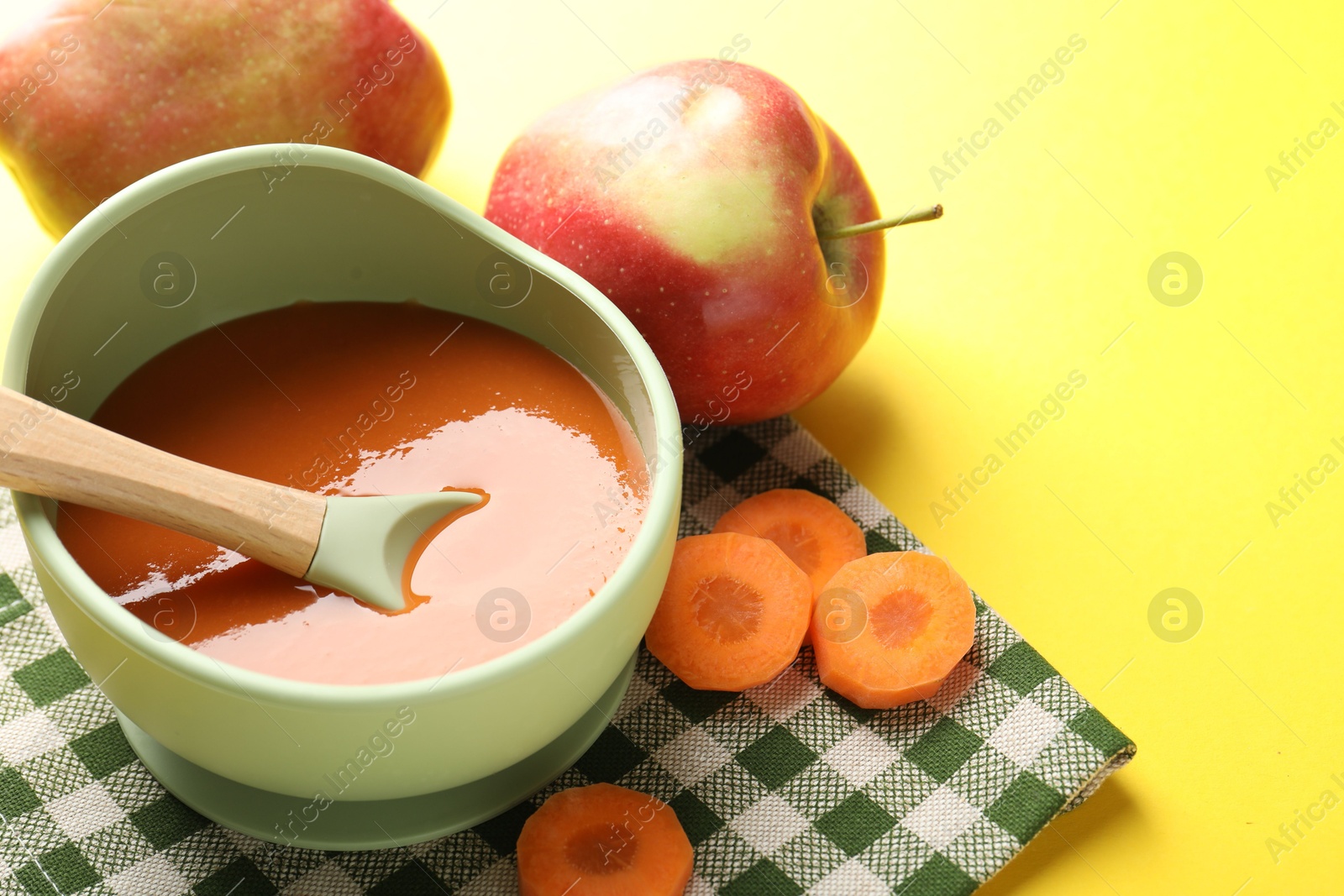 Baby food. Tasty puree in bowl and ingredients on yellow background, closeup Photo of Baby food. Tasty puree in bowl and ingredients on yellow background, closeup