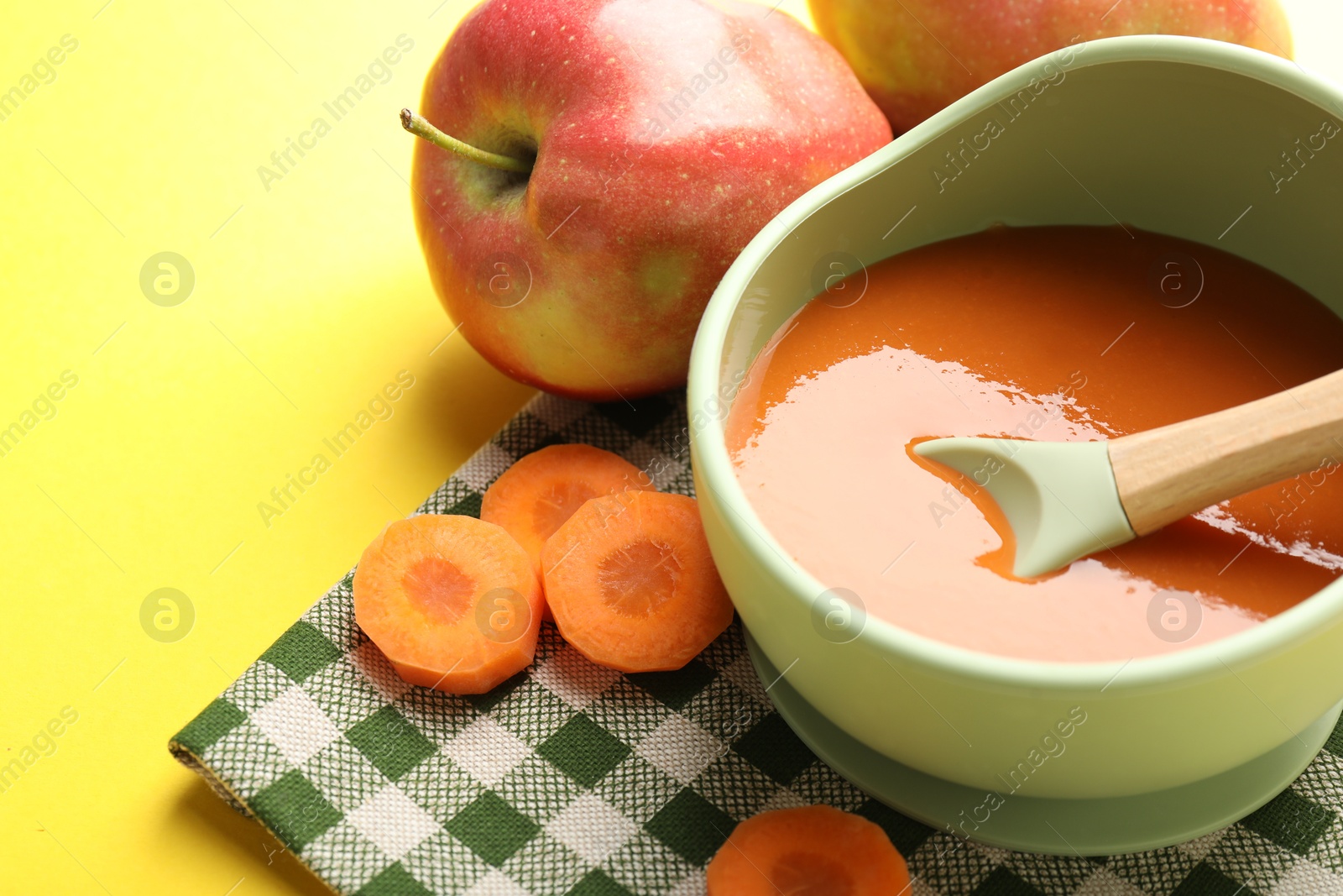 Baby food. Tasty puree in bowl and ingredients on yellow background, closeup Photo of Baby food. Tasty puree in bowl and ingredients on yellow background, closeup