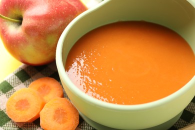 Photo of Baby food. Tasty puree in bowl and ingredients on table, closeup
