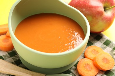 Photo of Baby food. Tasty puree in bowl and ingredients on table, closeup