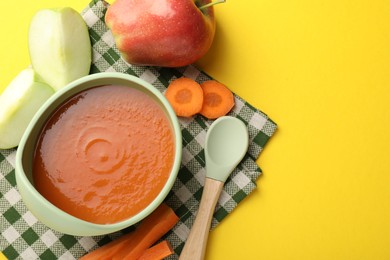 Photo of Baby food. Tasty puree in bowl and ingredients on yellow background, flat lay. Space for text