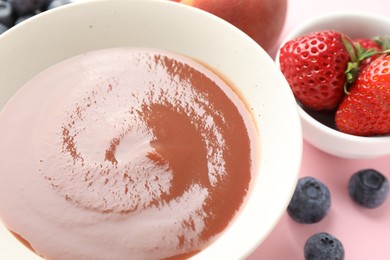 Photo of Baby food. Tasty puree in bowl and ingredients on pink background, closeup