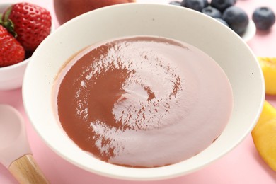 Photo of Baby food. Tasty puree in bowl and ingredients on pink background, closeup