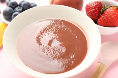 Photo of Baby food. Tasty puree in bowl and ingredients on pink background, closeup