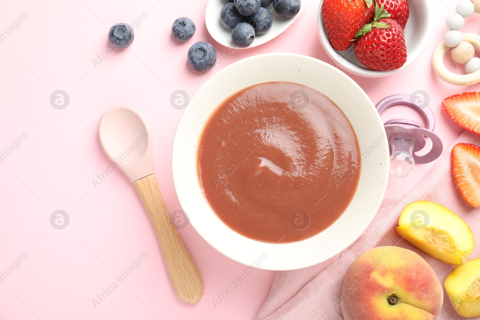 Photo of Baby food. Tasty puree in bowl, pacifier, teether and ingredients on pink background, flat lay