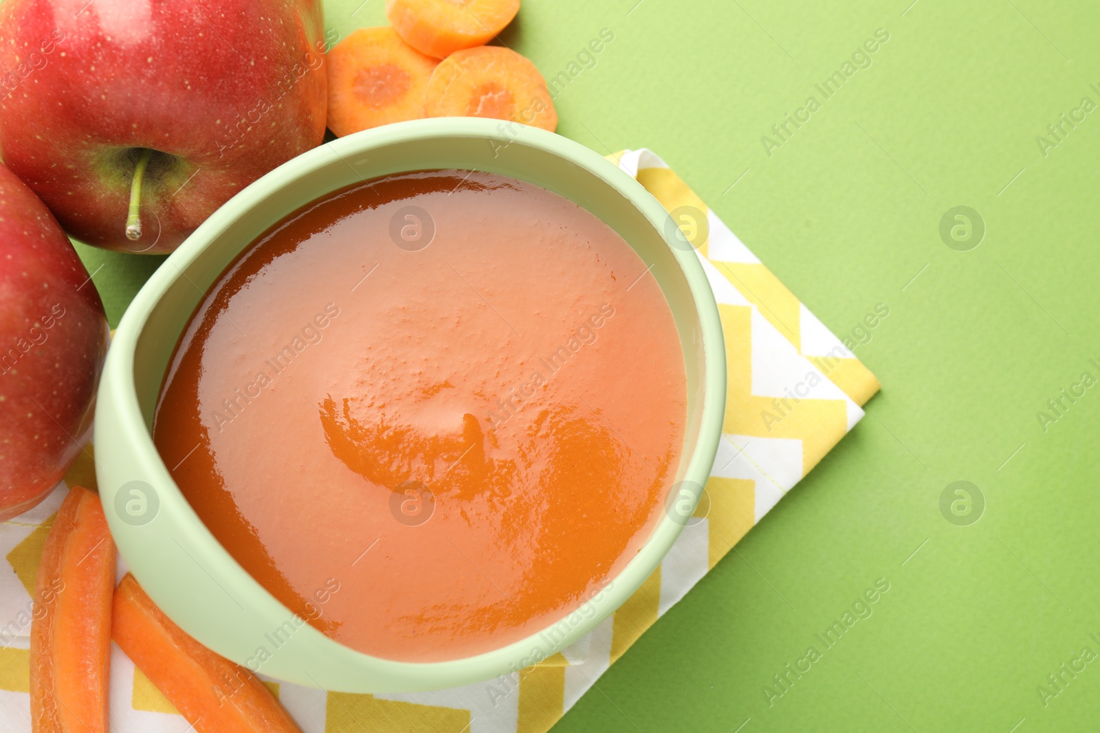 Baby food. Tasty puree in bowl and ingredients on green background, above view. Space for text Photo of Baby food. Tasty puree in bowl and ingredients on green background, above view. Space for text