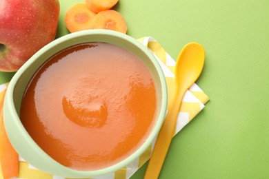 Photo of Baby food. Tasty puree in bowl and ingredients on green background, flat lay. Space for text