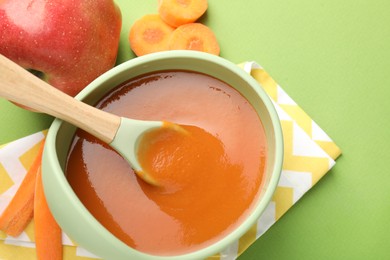 Photo of Baby food. Tasty puree in bowl and ingredients on green background, above view. Space for text