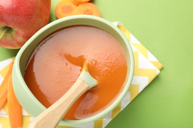 Photo of Baby food. Tasty puree in bowl and ingredients on green background, above view. Space for text