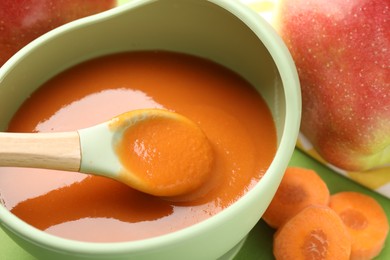 Photo of Baby food. Tasty puree in bowl and ingredients on green background, closeup