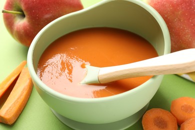 Photo of Baby food. Tasty puree in bowl and ingredients on green background, closeup
