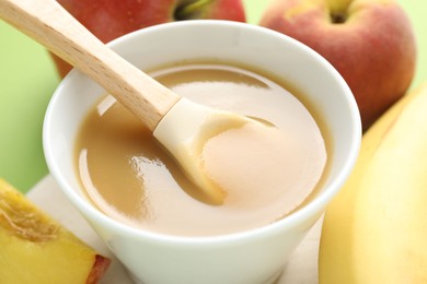Photo of Baby food. Tasty puree in bowl and ingredients on green background, closeup