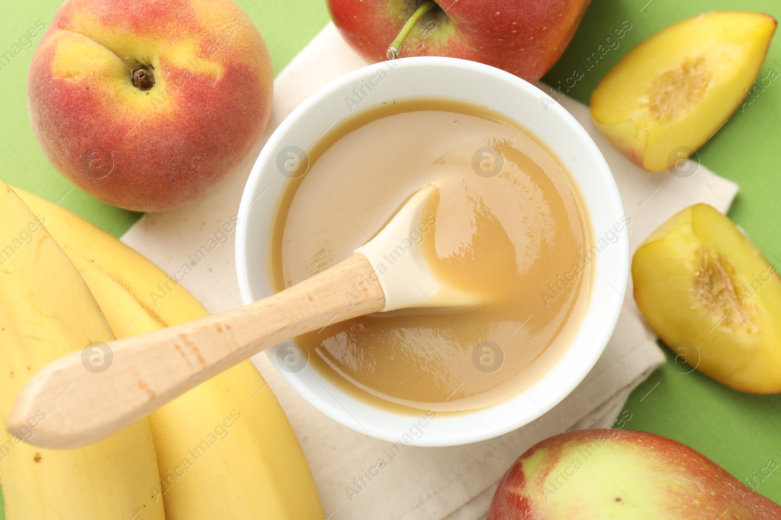 Baby food. Tasty puree in bowl and ingredients on green background, flat lay Photo of Baby food. Tasty puree in bowl and ingredients on green background, flat lay