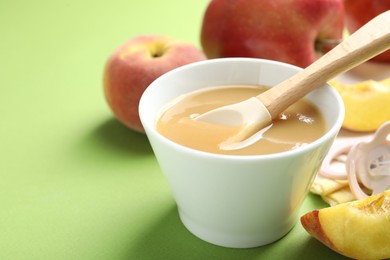 Photo of Baby food. Tasty puree in bowl and ingredients on green background, closeup. Space for text