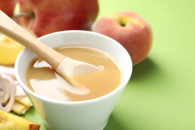 Photo of Baby food. Tasty puree in bowl and ingredients on green background, closeup. Space for text