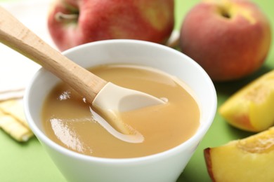 Photo of Baby food. Tasty puree in bowl and ingredients on green background, closeup