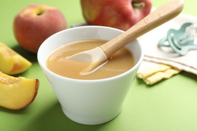 Photo of Baby food. Tasty puree in bowl and ingredients on green background, closeup