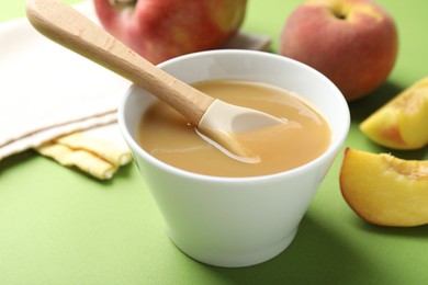 Photo of Baby food. Tasty puree in bowl and ingredients on green background, closeup