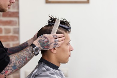Photo of Professional barber working with client in barbershop, closeup. Space for text